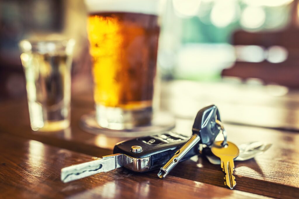 Llaves del coche junto a una copa: exclusiones por alcohol en el seguro de vida