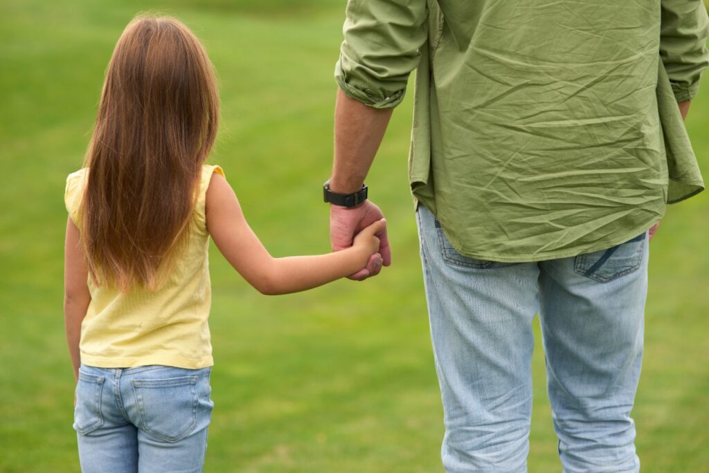 Padre e hija caminando de la mano: seguro de vida y pensión de alimentos