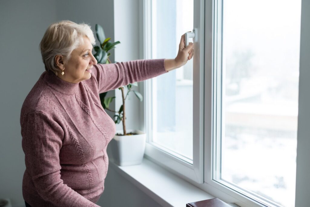Mujer mayor junto a la ventana: seguro de vida y pensión de viudedad